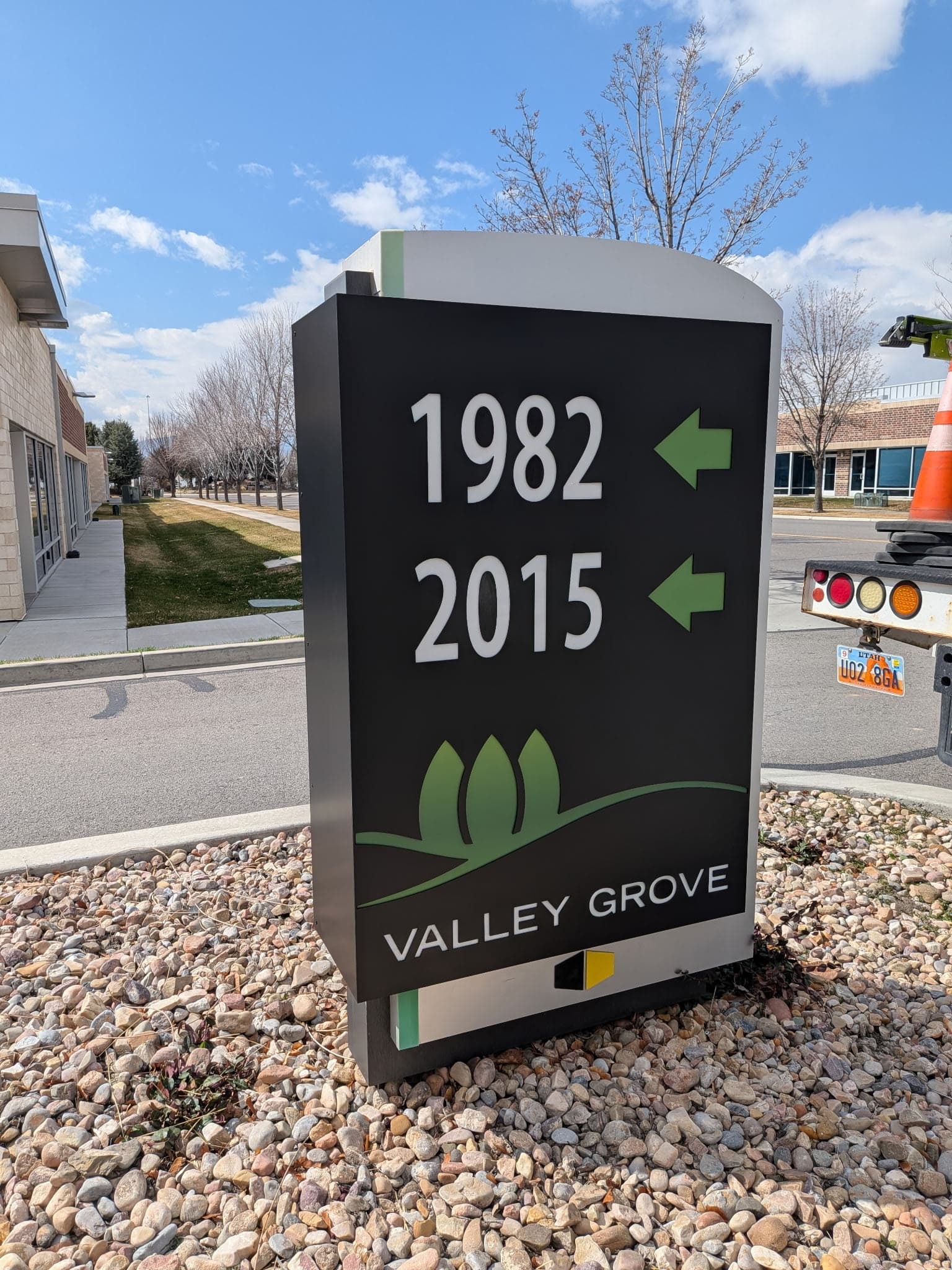 Outdoor directional monument sign for Valley Grove showing address numbers 1982 and 2015 with green arrows.