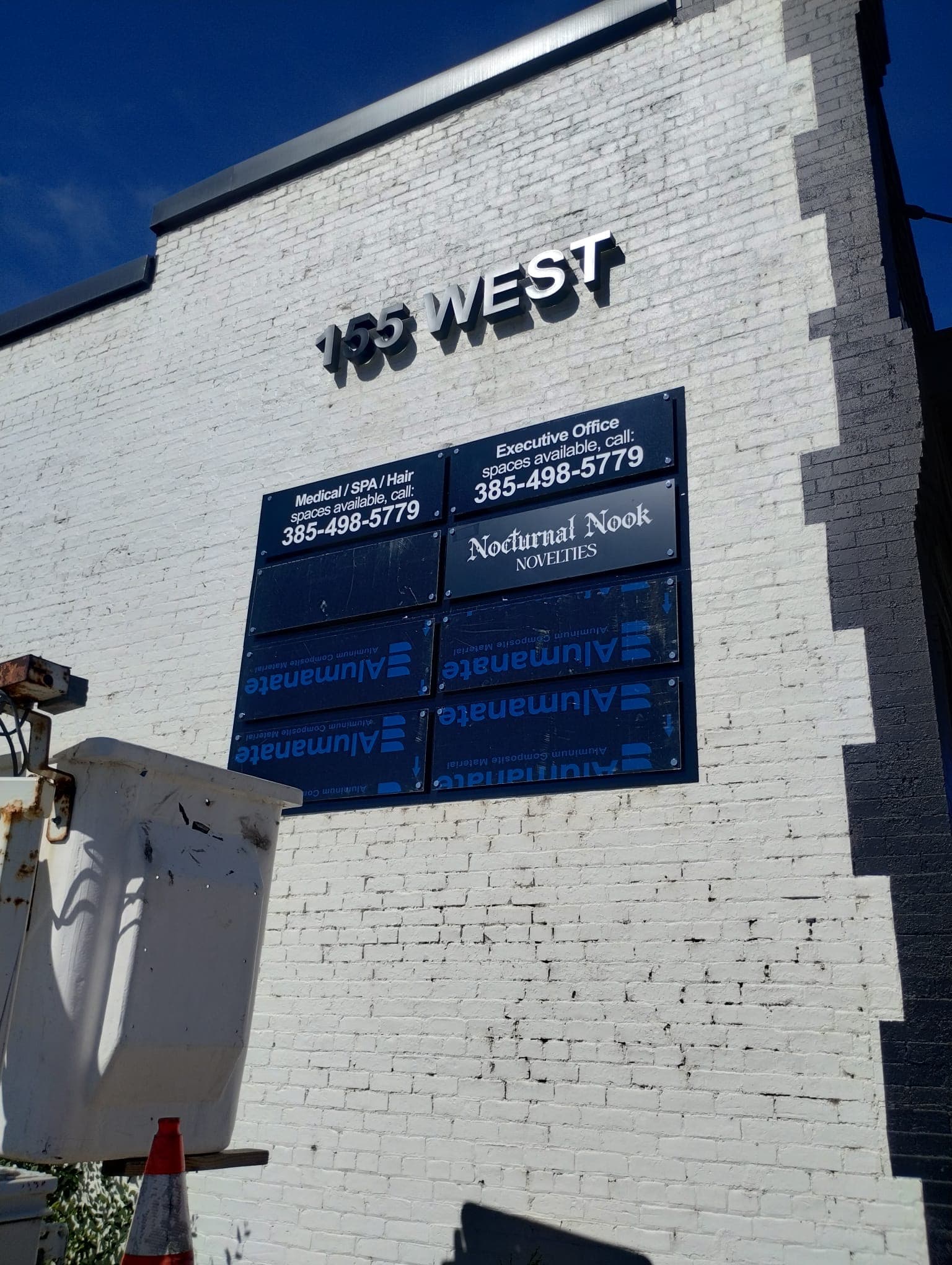 Exterior brick building featuring 155 West dimensional letters and tenant directory panel installation.