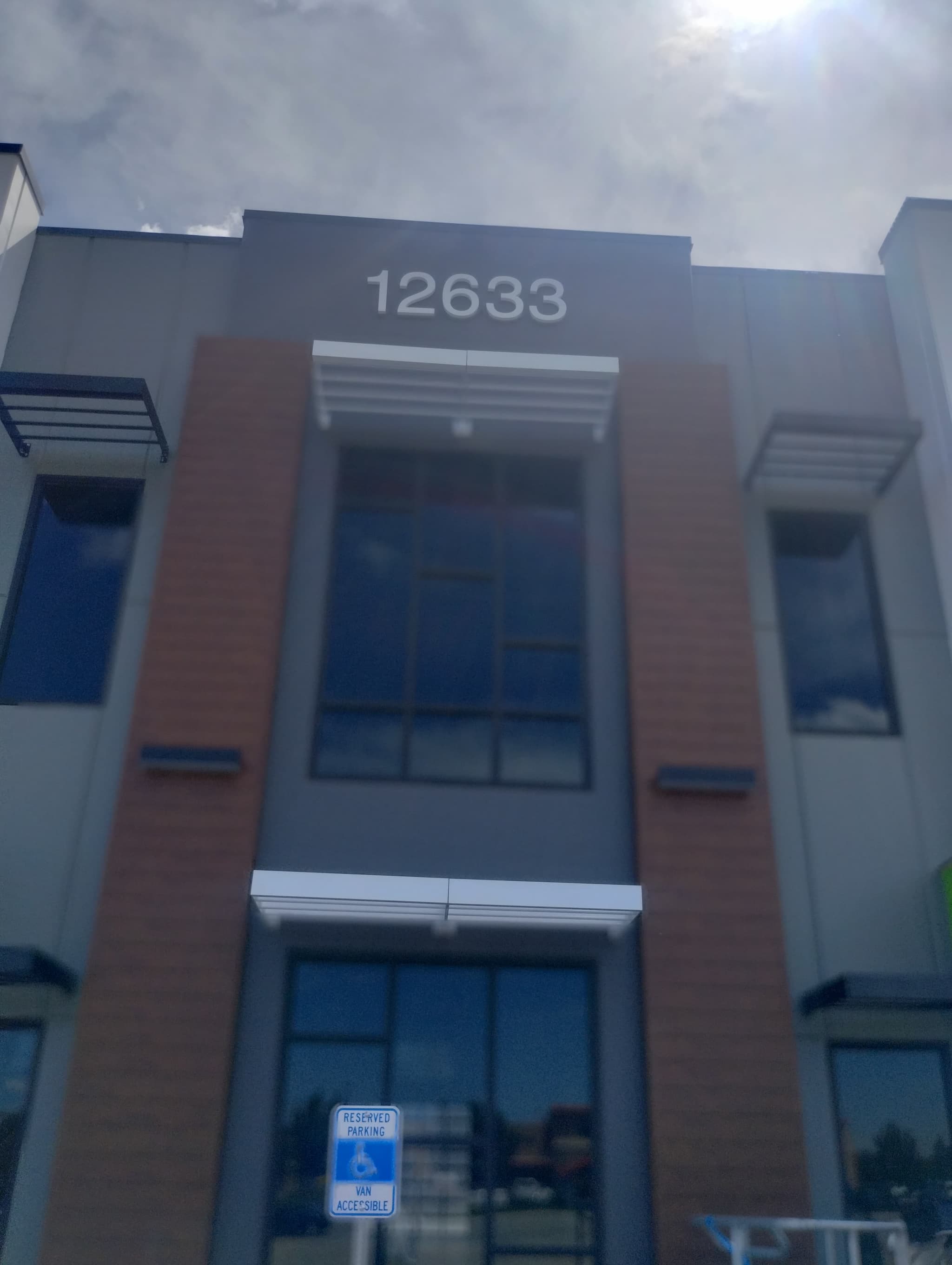 Exterior facade of a modern commercial building with large glass windows and address number 12633 mounted above.