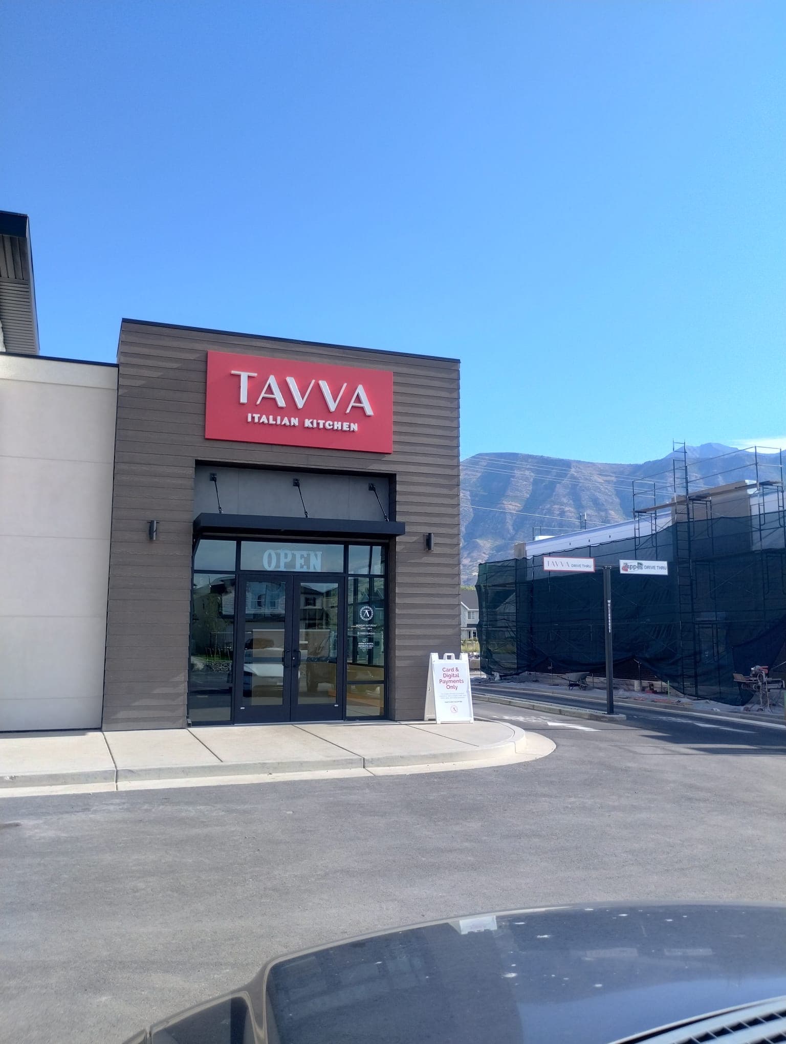 Exterior storefront of Tavva Italian Kitchen featuring a red illuminated building sign and entrance doors.